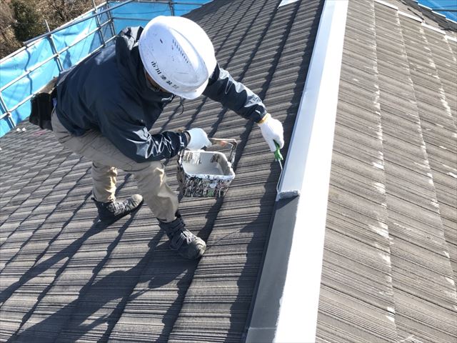 スレート屋根をローラーで塗装している施工中の写真