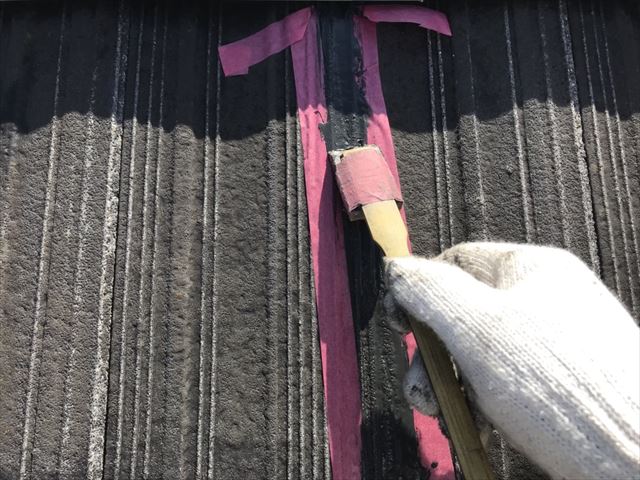 スレート屋根の補修箇所を塗装前に下地処理している施工状況
