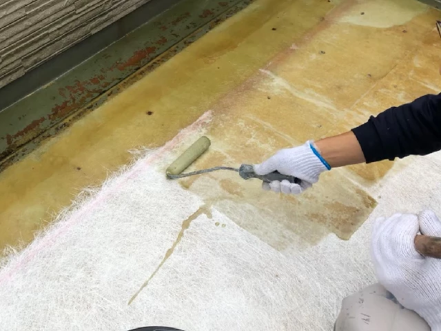 ガラスマットと樹脂でベランダのFRP防水層を補修している施工写真
