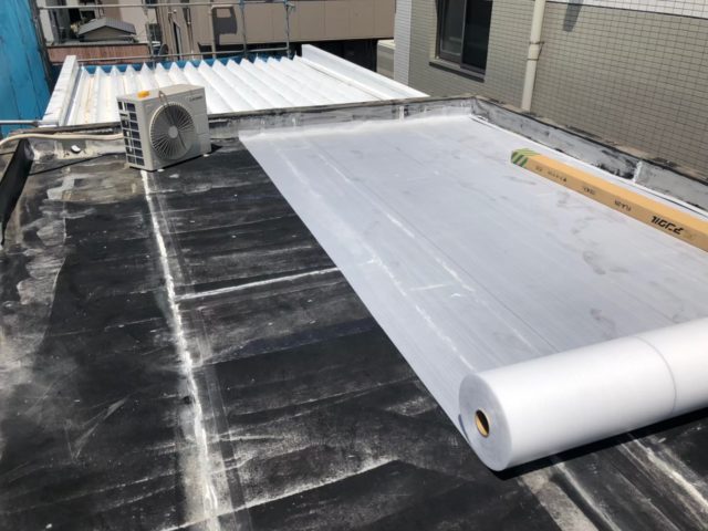 沼津市新宿町の屋上で黒い既存ゴムシート防水を残し、その上に通気マットを敷いている施工写真